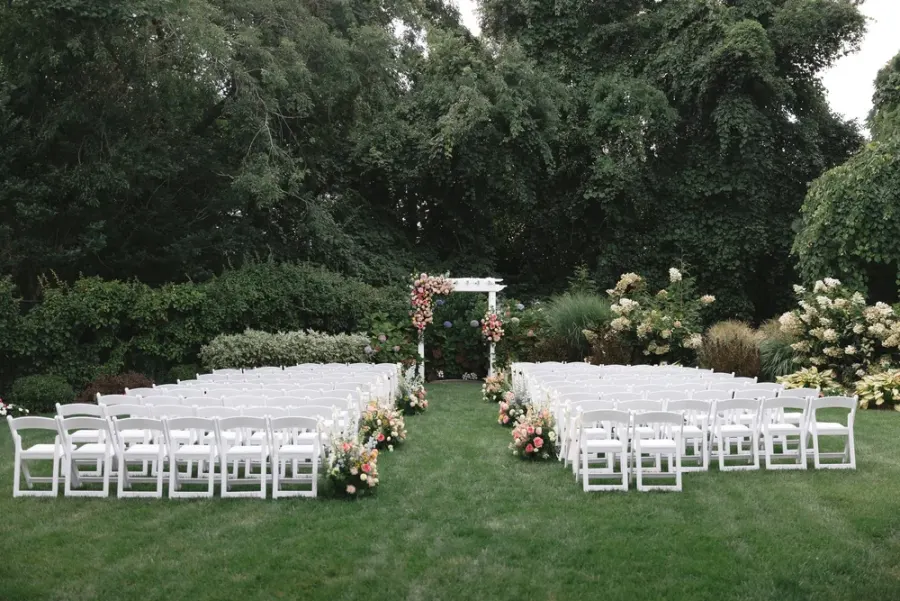 White chairs set for a ceremony on the back lawn