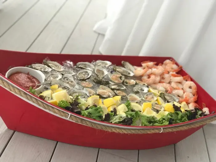 Raw bar of oysters and shrimp in a red boat